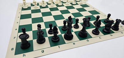 Close-up view of black Staunton-style chess pieces on a green and white vinyl board with algebraic notation.