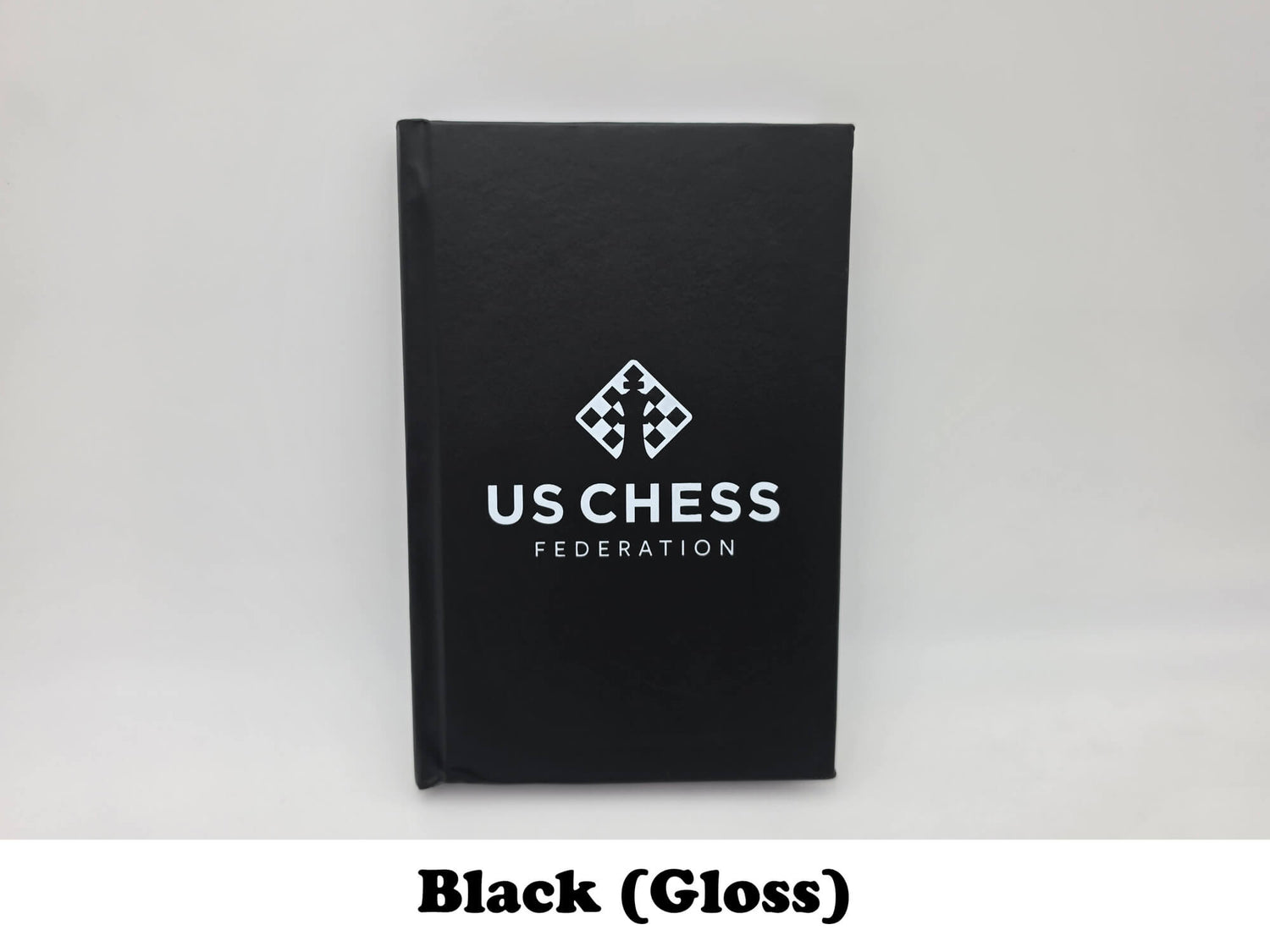 Glossy black USCF chess scorebook with official logo front cover view.