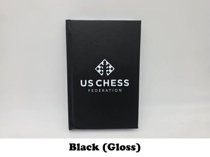 Glossy black USCF chess scorebook with official logo front cover view.