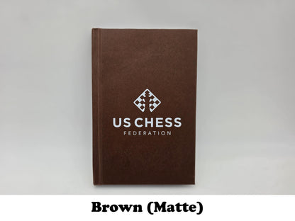 Matte finish brown USCF chess notation scorebook with official logo.