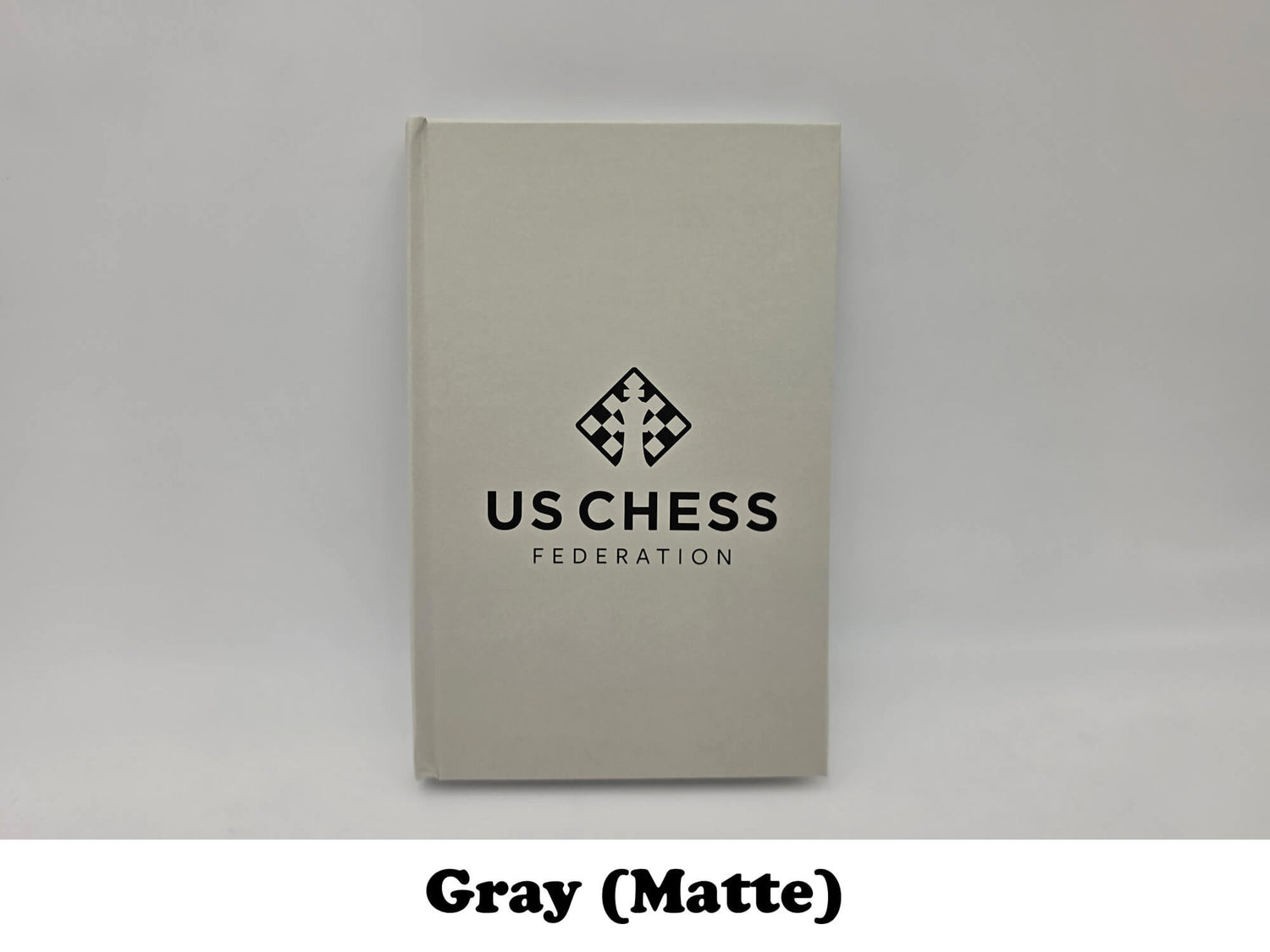 Matte light gray USCF official chess scorebook.