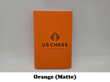 Matte orange USCF official chess scorebook.