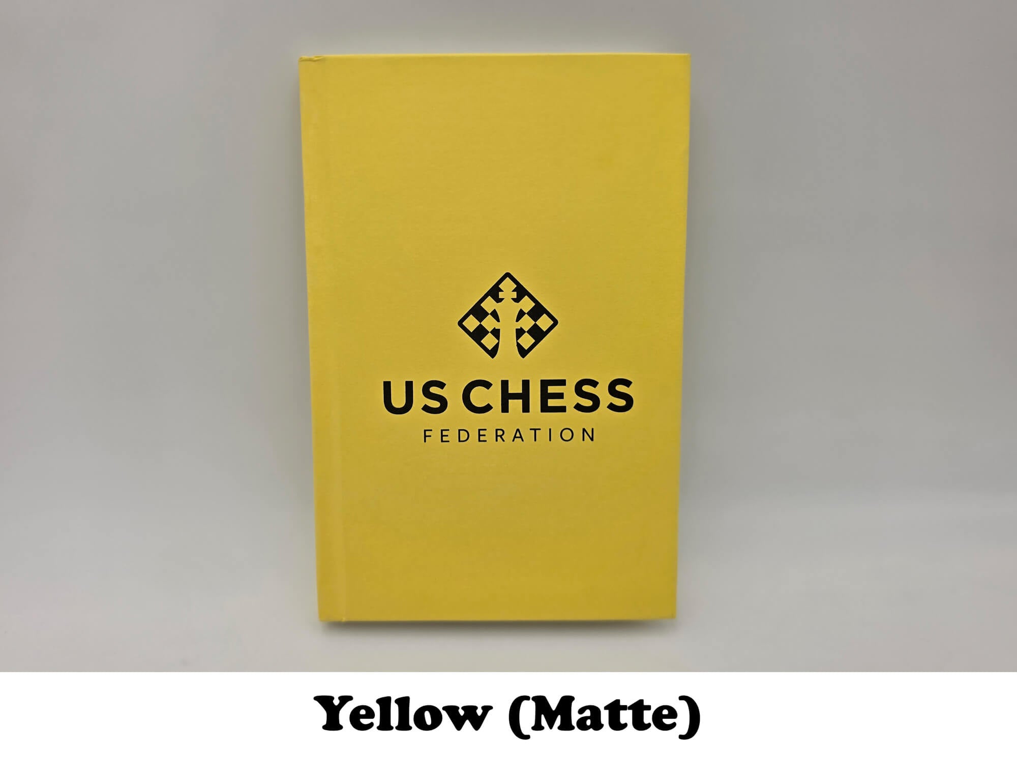Bright yellow matte USCF chess scorebook.
