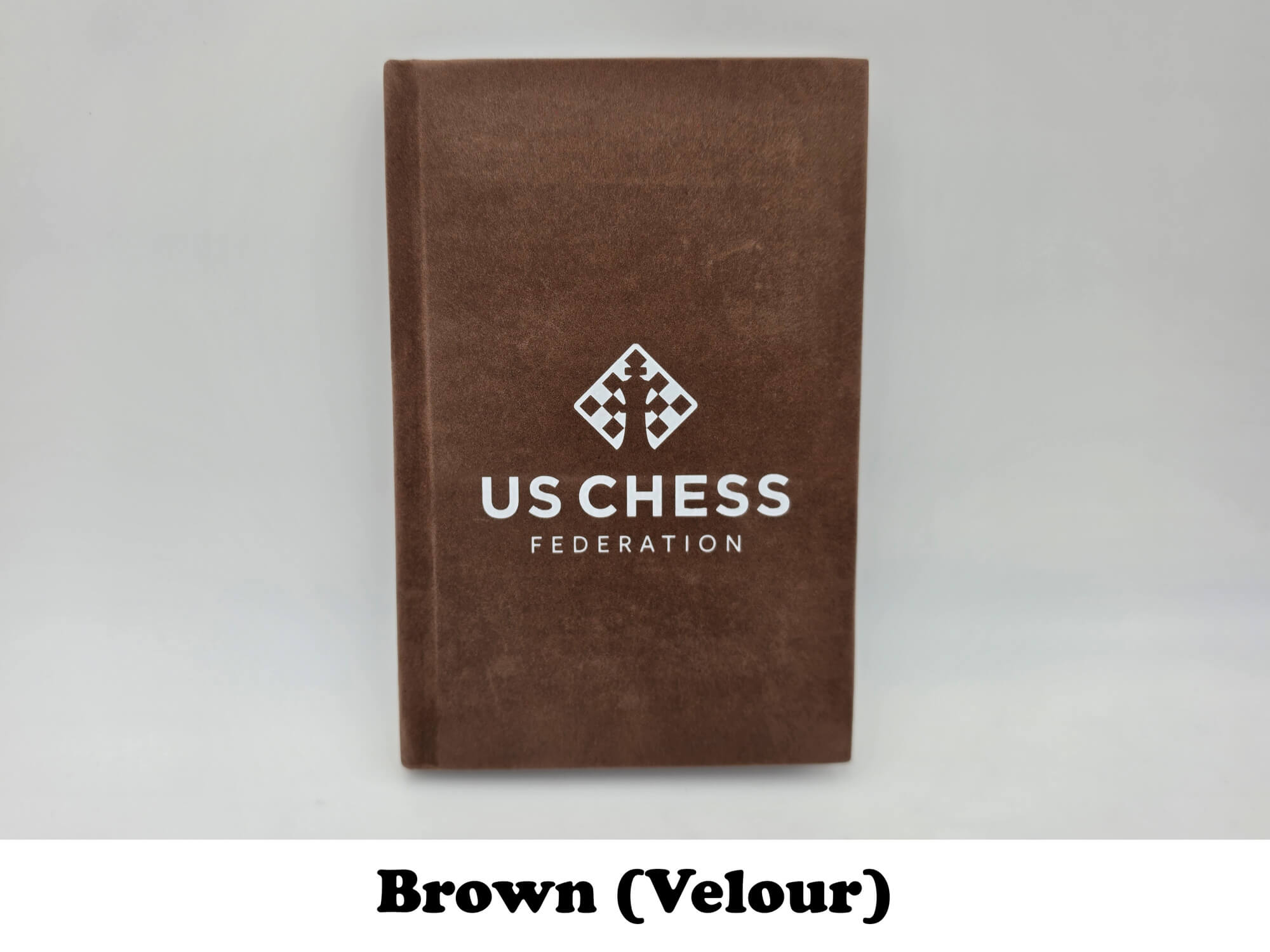 Soft brown velour USCF chess scorebook cover with official logo stamp.